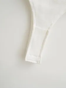 Detailed close-up of the snap closure and ribbed fabric on a white bodysuit top
