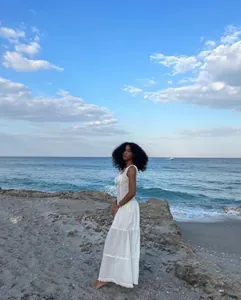 Elegante vestido maxi blanco de vacaciones con volantes en un entorno de playa