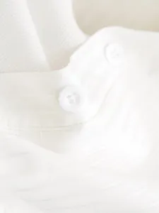 Close-up detail of a white textured bodysuit shirt with small collar and buttons