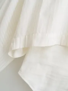 Close-up detail of white striped shirt bodysuit showing fine fabric texture and seams
