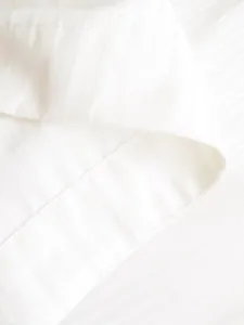 Close-up detail of white striped fabric and fine stitching on the cuff of a bodysuit.