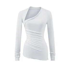 Détail d'un haut blanc ajusté à manches longues avec col asymétrique et fronces latérales.