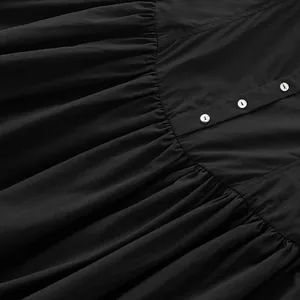 Detalle de primer plano del cierre de botones frontal y tela plisada de un vestido negro