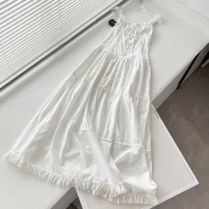 Detalle de vestido largo blanco de capas con volantes y botones para un estilo vacacional