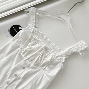 Detalle de vestido largo blanco plisado con tirantes de volantes y lazo en el pecho.