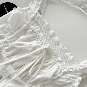 Primer plano de vestido blanco de verano con cuerpo nido de abeja y volantes finos