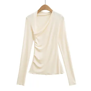 Gros plan d'un t-shirt crème asymétrique à manches longues et coupe ajustée