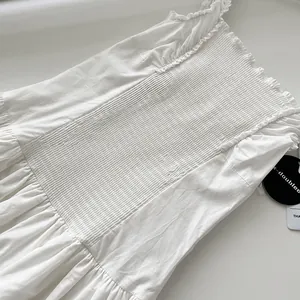 Primer plano de un vestido largo blanco de verano con cuerpo fruncido y volantes