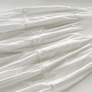 Primer plano de los volantes plisados blancos y la tela fruncida de un maxi vestido