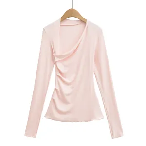 Vue détaillée d'un haut rose ajusté à manches longues avec un décolleté asymétrique