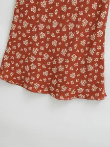Détail de l'ourlet et du motif floral blanc sur une jupe midi de couleur rouille vintage.
