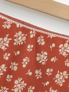 Détail d'un tissu de jupe à fleurs avec bordure en dentelle blanche et base orange rouille.