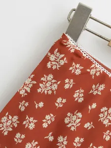 Détail d'une jupe midi fleurie rouge rouille avec une bordure en dentelle blanche