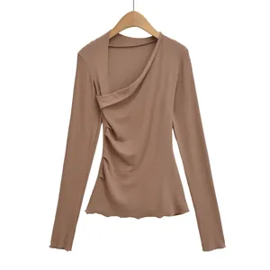 Détail du haut à manches longues marron avec encolure asymétrique et plis latéraux