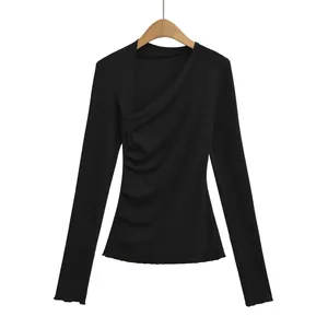 Détail d'un haut noir à manches longues avec décolleté asymétrique et plis latéraux élégants