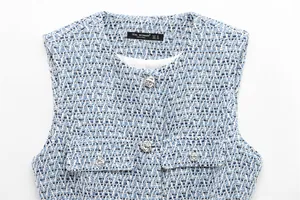Vue détaillée d'un gilet en tweed bleu et blanc avec des boutons métalliques argentés