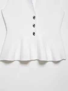 Detail der weißen Strickweste mit Rüschensaum und drei silbernen Metallknöpfen.