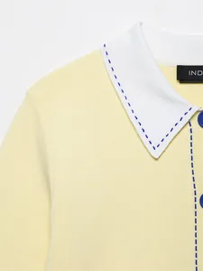 Détail d'un pull en tricot jaune avec col blanc et surpiqûres bleues contrastées