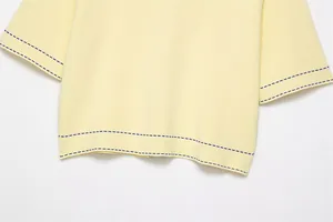 Detail of blue contrast stitching on light yellow knit Polo shirt sleeve