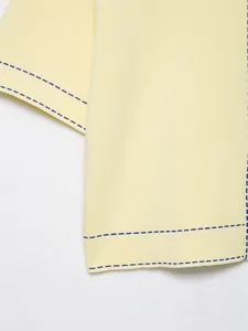 Vue macro d'un tricot jaune clair avec détail de couture en pointillés bleus élégants