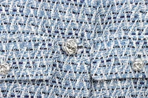 Détail macro du tissu tweed bleu avec fil métallique et boutons nœuds argentés