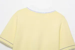 Close-up of yellow knitted polo shirt with blue contrast stitching and white collar