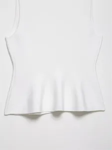Detailansicht des eleganten, gerüschten Schößchensaums an einem weißen Strickoberteil.