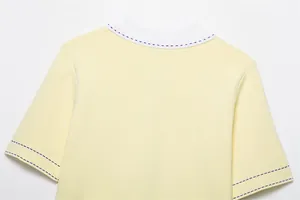 Gros plan d'un pull en tricot jaune avec col blanc et surpiqûres contrastées bleues.