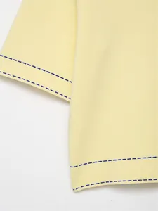 Macro view showing the fine knit texture and blue stitched hem of a yellow polo shirt