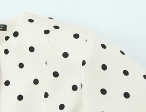 Gros plan détaillé d'un blazer vintage français à pois noirs sur tissu crème