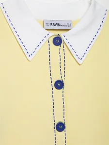 Detail view of yellow knit polo shirt featuring blue contrast stitching and white collar