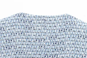 Gros plan sur la texture d'un gilet en tweed bleu et blanc avec des fils métalliques.