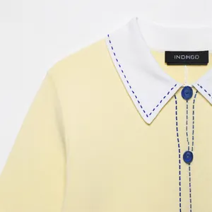 Élégant polo en maille jaune pâle avec col blanc et surpiqûres contrastées bleues détails.