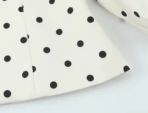 Détail en gros plan d'un blazer rétro français blanc à motif de pois noirs