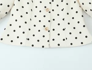 Gros plan d'un blazer rétro français à pois avec des boutons décoratifs dorés élégants
