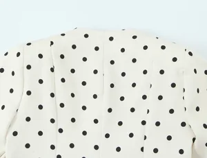 Vue rapprochée du motif à pois noirs et des coutures d'épaule du blazer rétro chic.