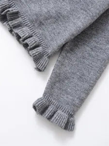 Detail shot of the ruffled cuff on a grey knit sweater showing soft texture