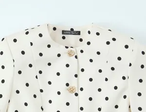Gros plan d'une veste française rétro à pois avec des boutons dorés en forme de nœud.
