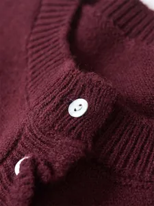 Close-up of burgundy knit sweater showing ribbed neckline and white pearl button details