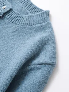 Close-up detail of a soft blue knitted sweater neckline showing premium fabric texture