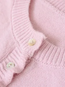 Close-up of a pink round neck knit sweater featuring elegant shell button details