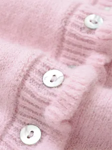 Close-up detail of iridescent pearl buttons on soft pink knitted sweater with ribbed texture