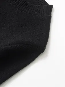 Detailed close-up view of a black knit sweater featuring ribbed crewneck collar texture