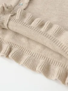 Close-up of beige knitted sweater showing intricate ruffle edge and soft texture