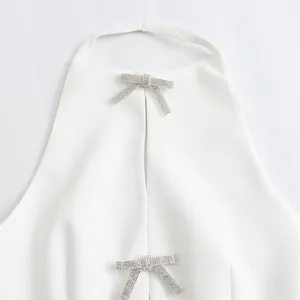 Detailed view of a white halter neck top with two elegant sparkling rhinestone bow accents