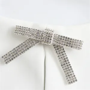 Close-up of elegant rhinestone-encrusted bow decoration on a white halter-neck top