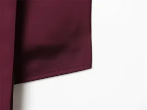 Nahaufnahme des glatten burgunderroten Stoffes und der sauberen Saumnaht eines Neckholder-Tops.