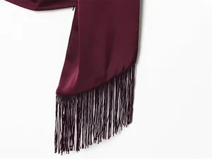 Nahaufnahme der langen Fransenquasten an einem luxuriösen weinroten Satin-Neckholder
