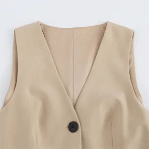 Close-up of the V-neckline and black button detail on a beige sleeveless vest dress