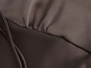 Primer plano macro de tela de satén de seda marrón con elegantes pliegues y textura.